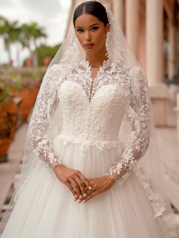 Νυφικό με μανίκια και μπούστο από ιδιαίτερη δαντέλα.