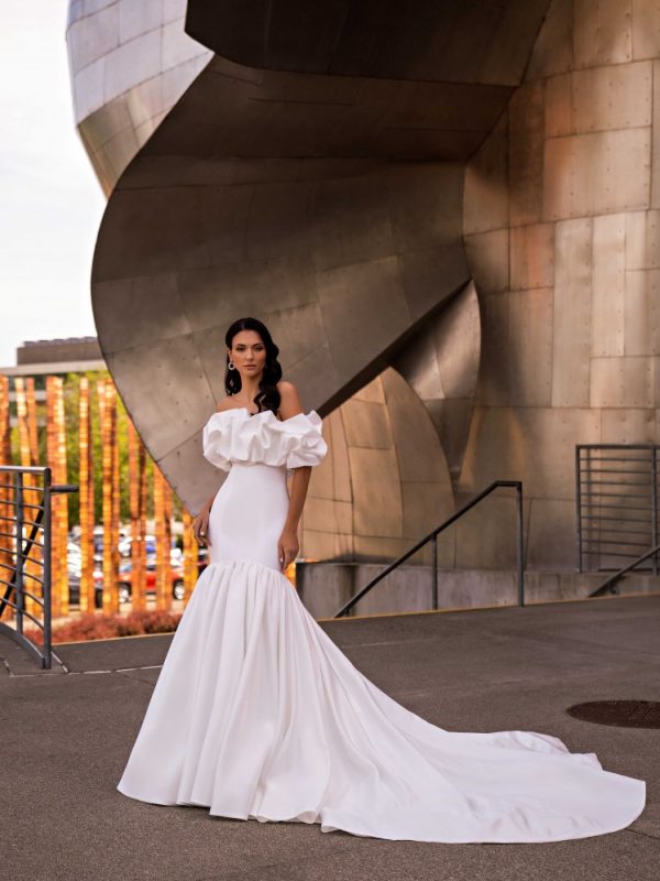 Αυτό το υπέροχο Νυφικό γοργόνα Sirena σε μινιμαλιστικό στυλ, με ακάλυπτους ώμους και σιλουέτα «γοργόνας» με ουρά, μαγνητίζει με την ομορφιά του. Το μοντέλο είναι φτιαγμένο από γυαλιστερό ύφασμα που του χαρίζει μια πολυτελή και εκλεπτυσμένη όψη.