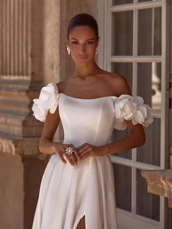 Χολιβουντιανό νυφικό με ανοιχτούς ώμους με τρισδιάστατα λουλούδια.